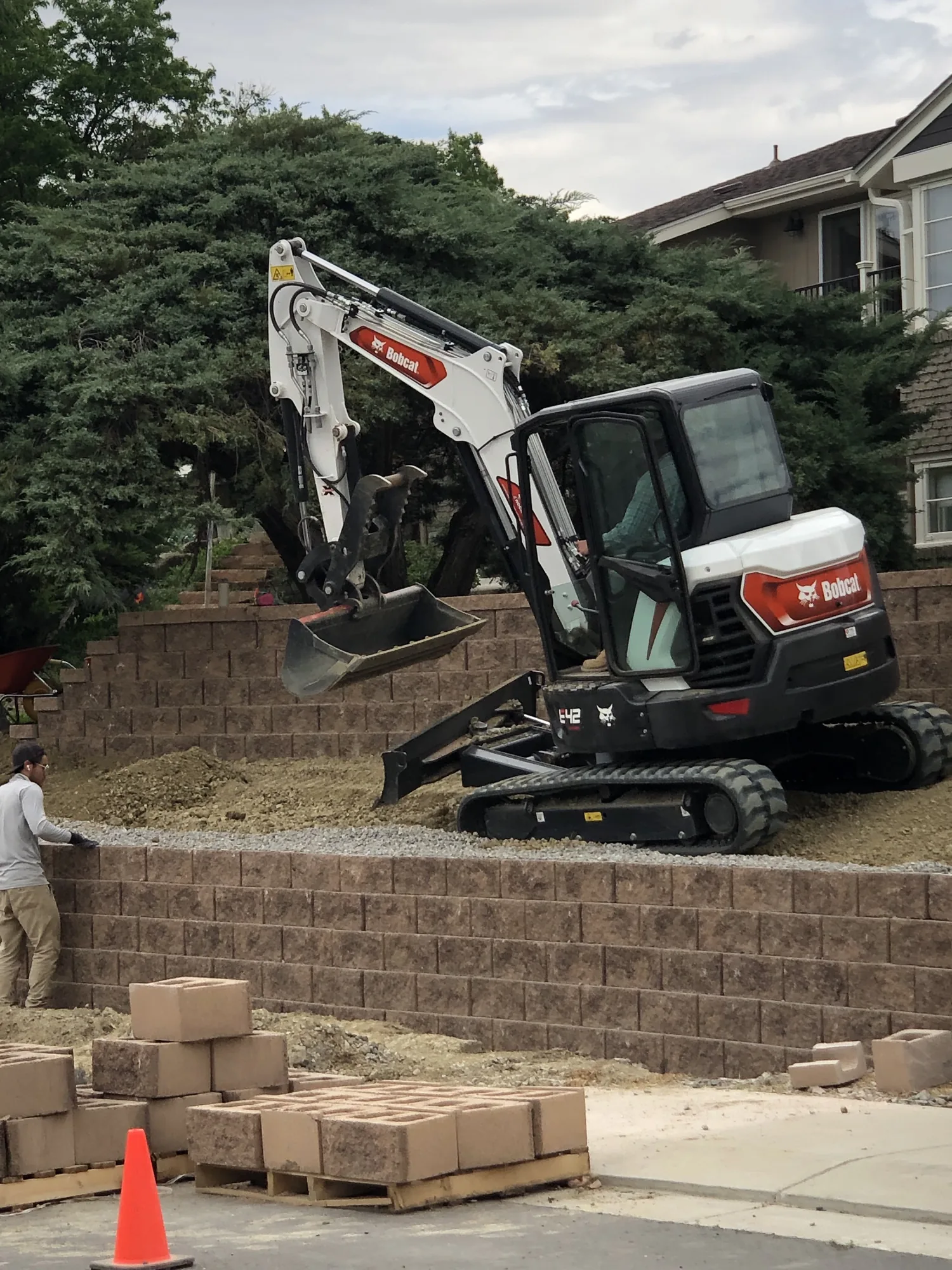 Excavator working beside a stepped retaining wall