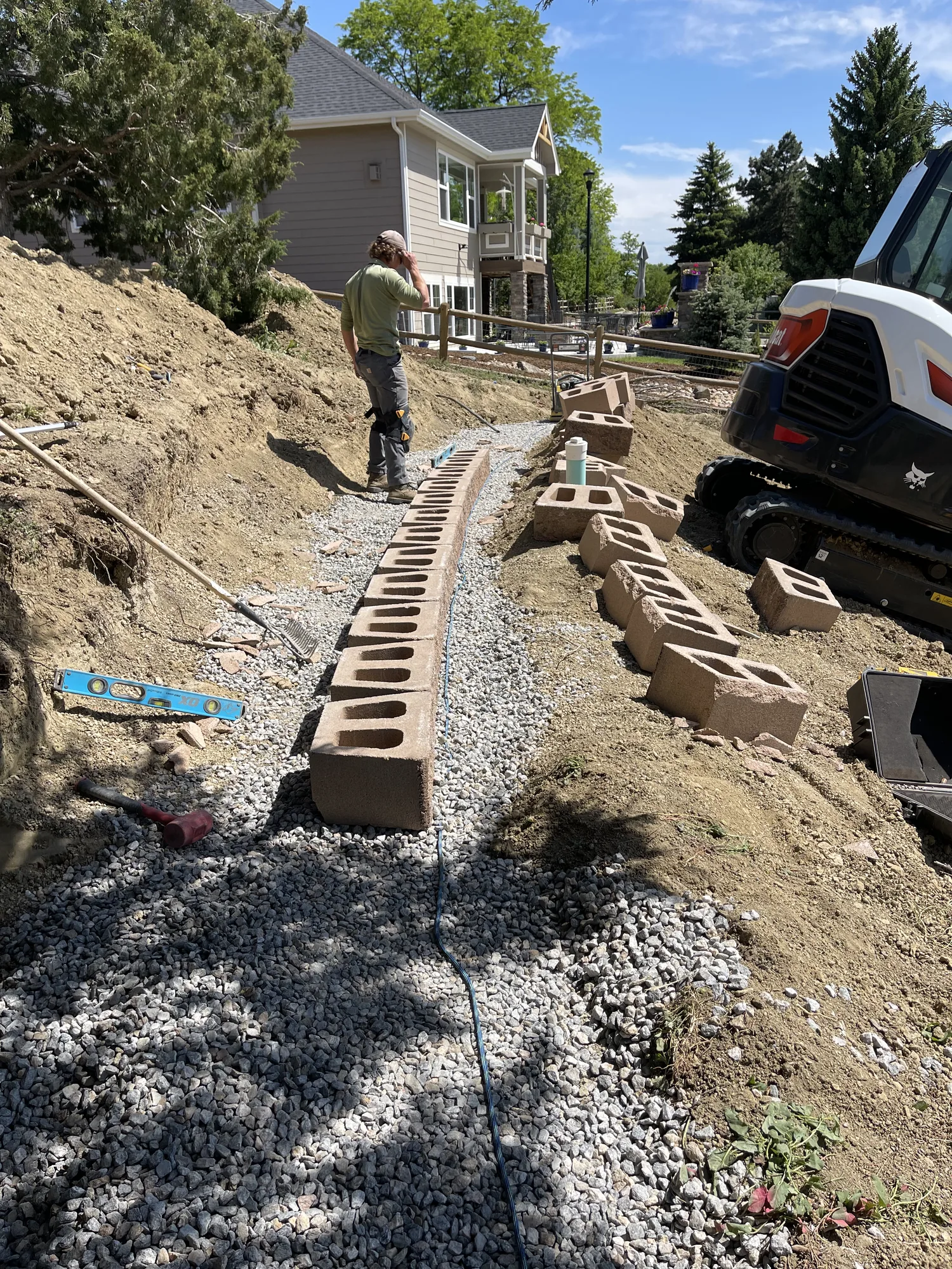 Retaining wall base course laid out beside a compact loader