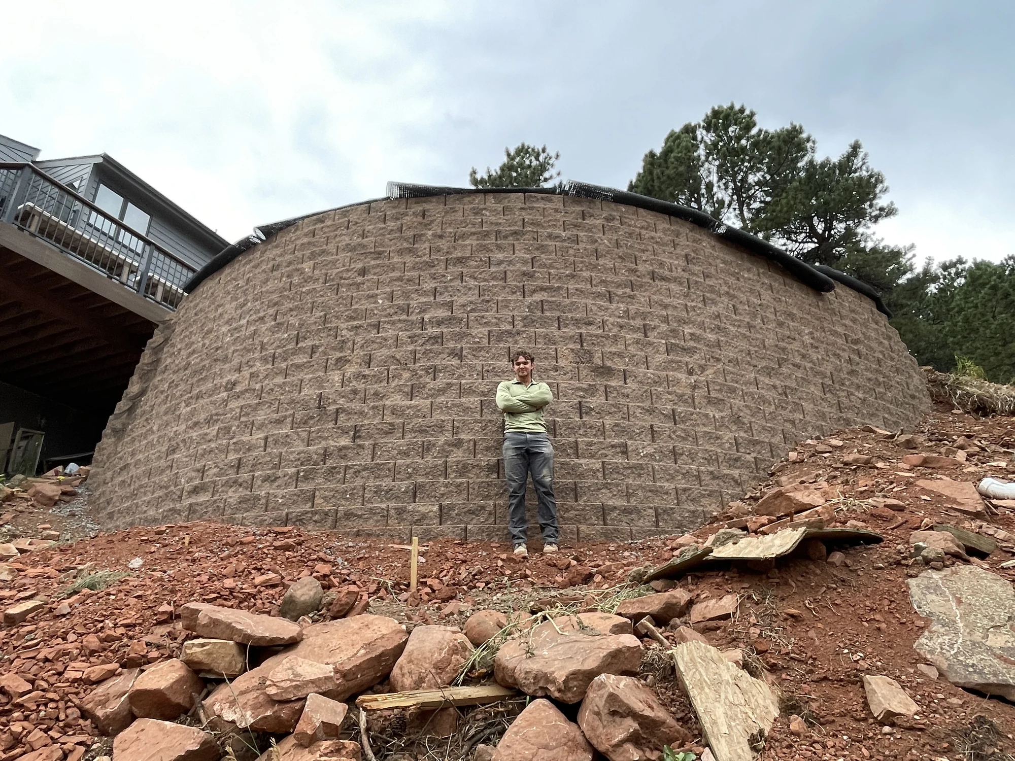 Builder standing in front of a completed curved retaining wall