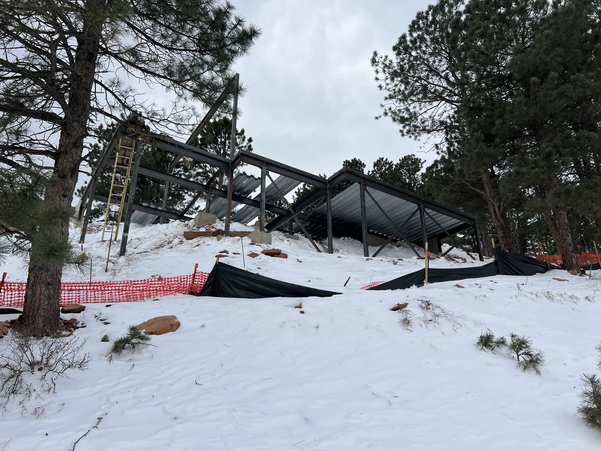 Steel structure under construction on a snowy wooded slope