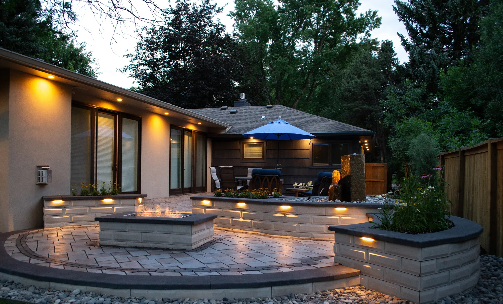 Completed courtyard with curved seat walls, a fire feature, water feature, and integrated lighting