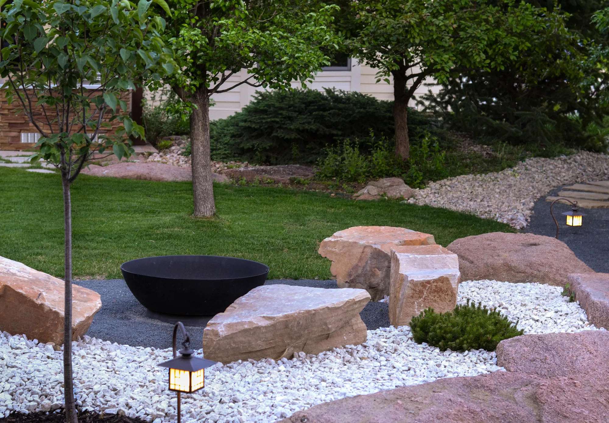 Black fire bowl centered within a white gravel garden